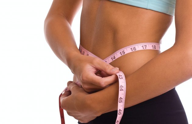 Woman measuring stomach with measuring tape